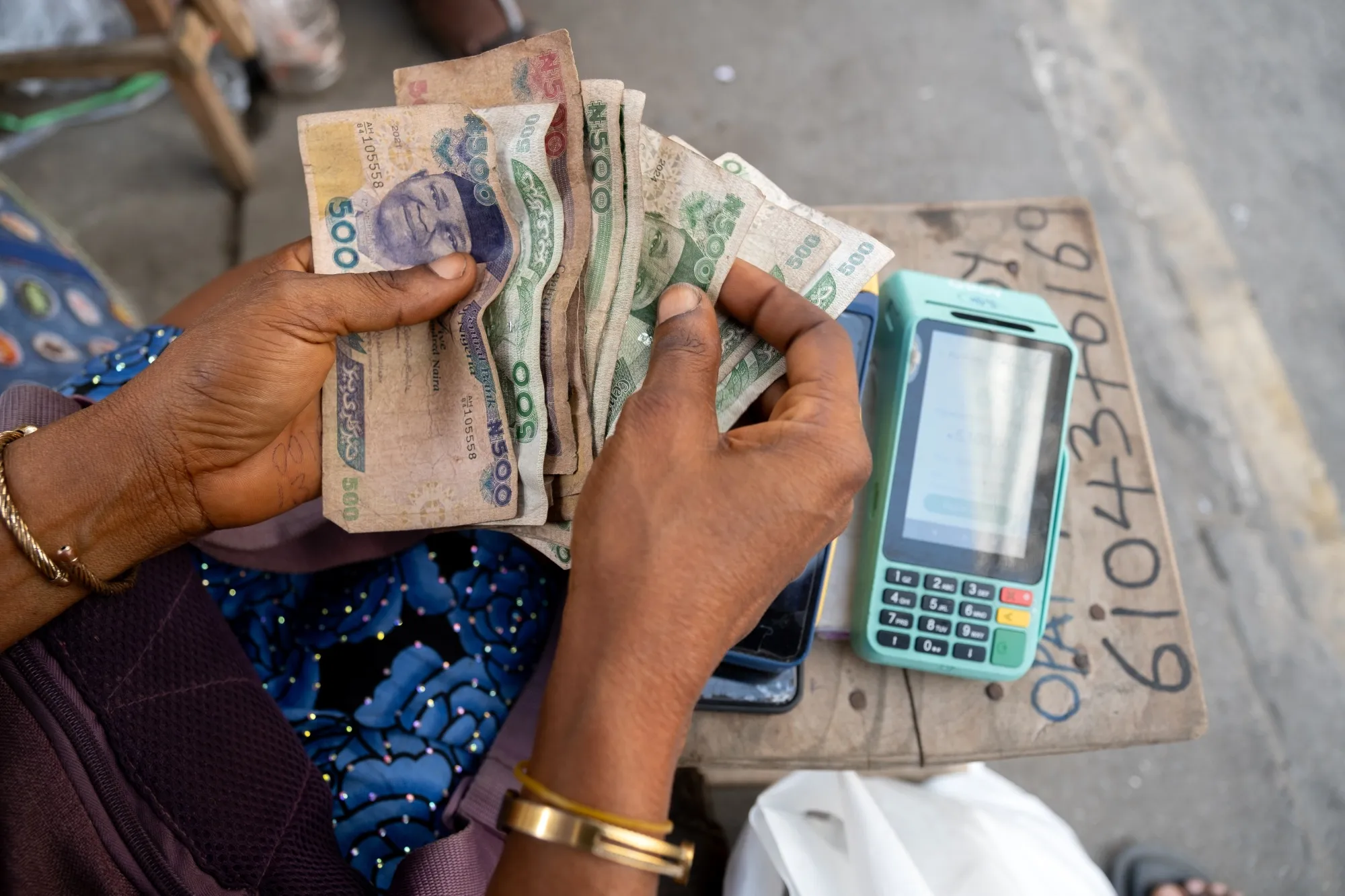 A point of sales operator processes counts cash during a transaction in Lagos.