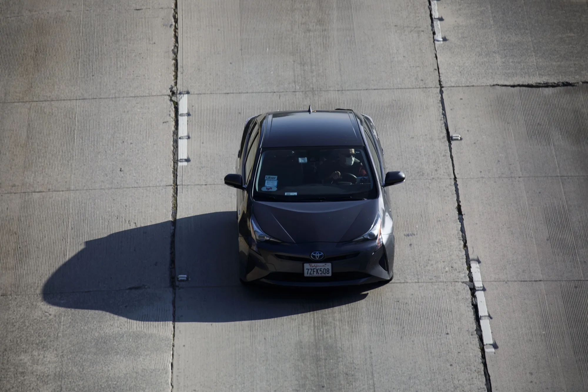 A person wears a protective mask while driving a vehicle displaying&nbsp;Lyft signage on an empty 110 freeway towards downtown Los Angeles, California&nbsp;on&nbsp;April 1.&nbsp;