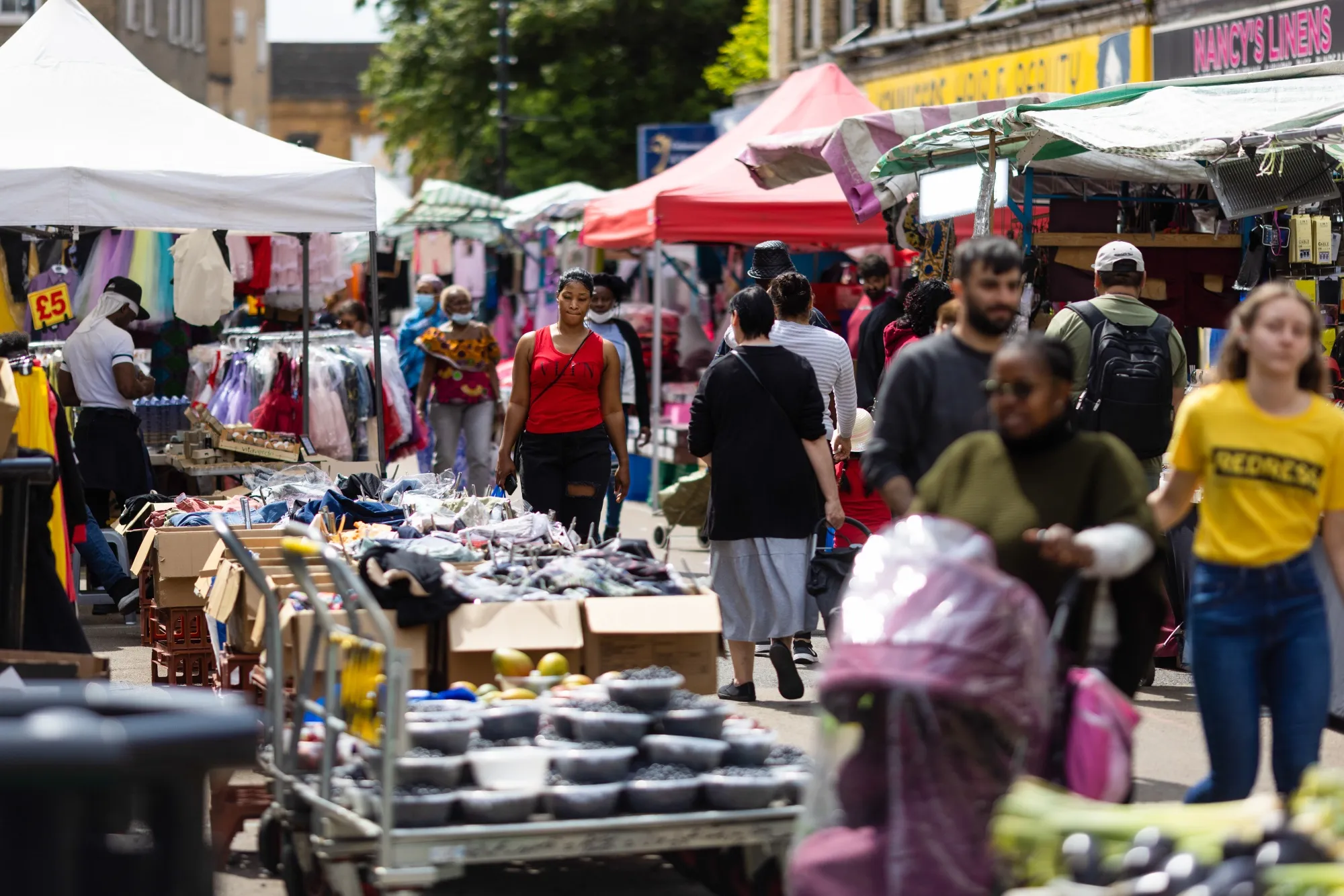 Customers walk between stalls at a street market in London, UK.