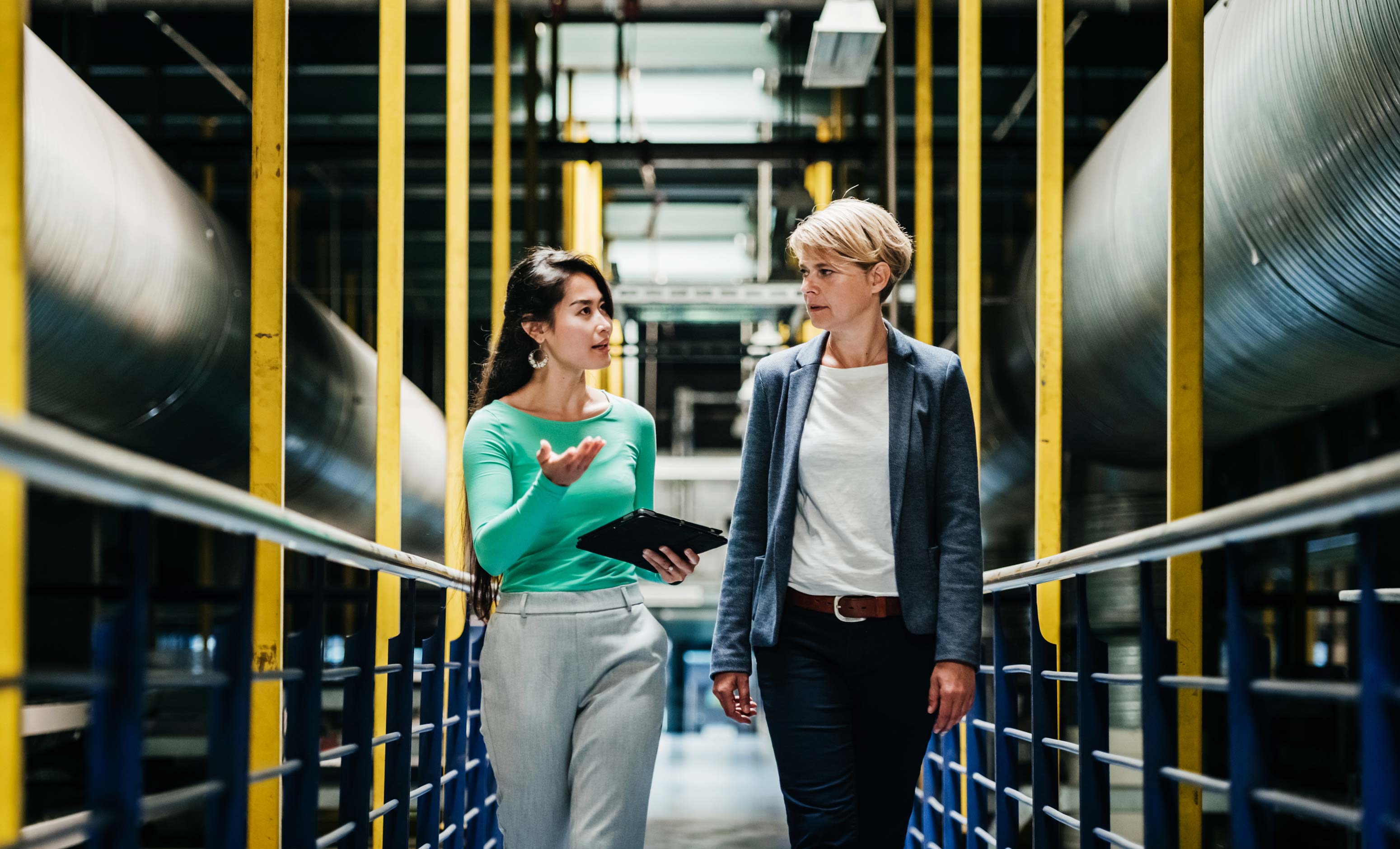 2 women talking work while holding a tablet